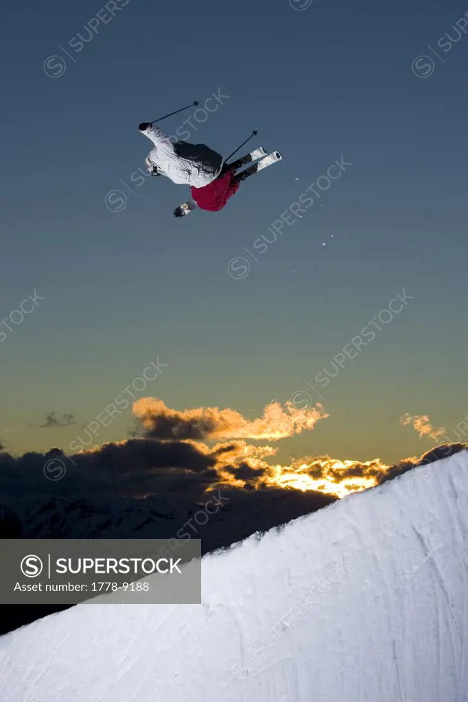 Skier does an air in half pipe at sunset