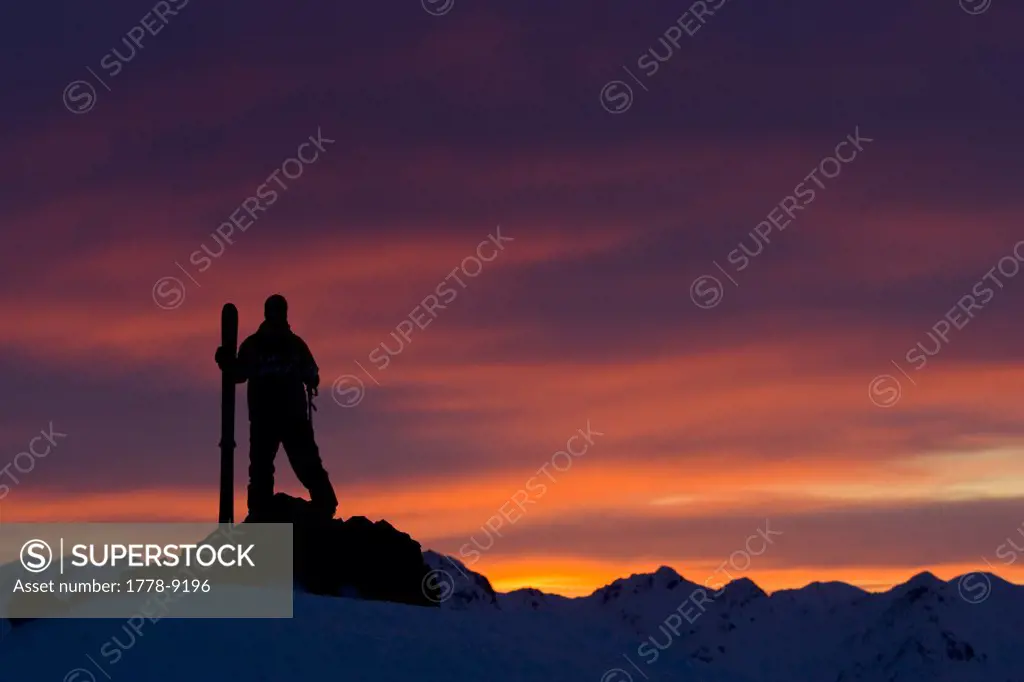 Skier watches sunset in the moutains