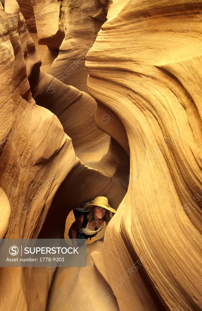 Woman explores twisting desert slot canyon, Escalante, Utah