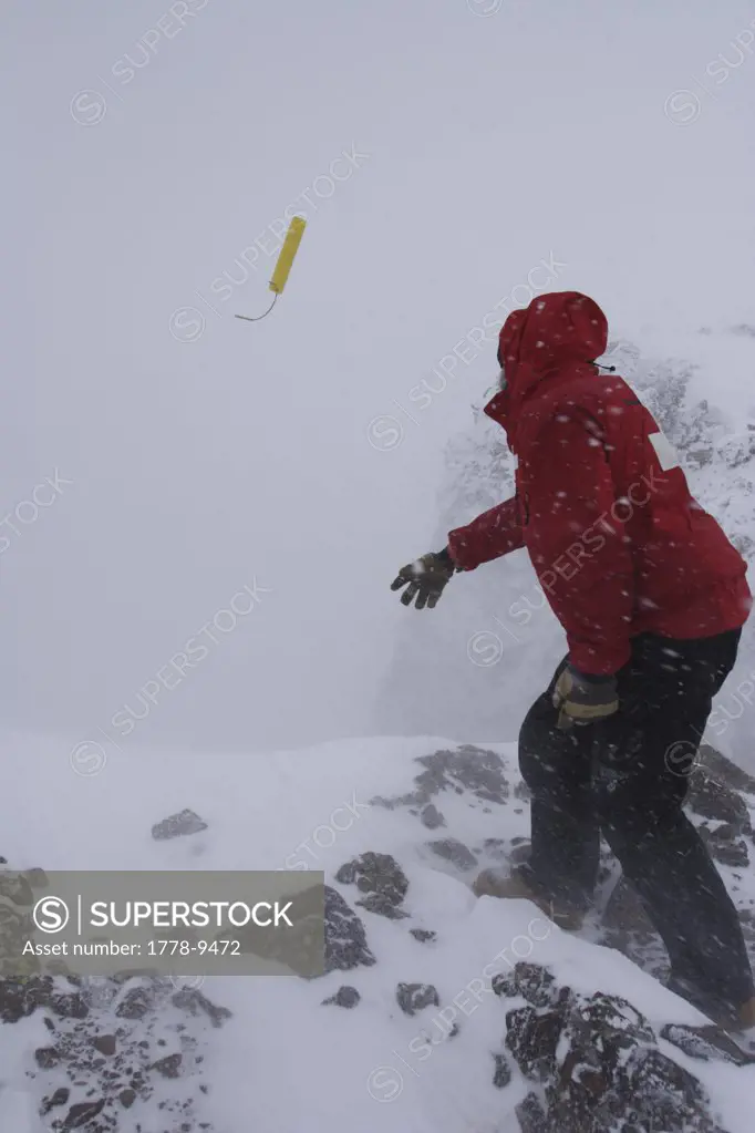 A ski patroller throws a stick of dynamite while on his snow safety route Ski patrollers throw dynamite to trigger potential av