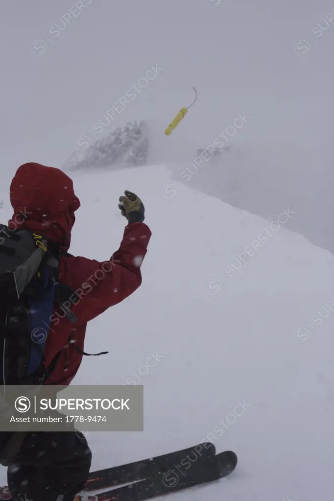 A ski patroller throws a stick of dynamite while on his snow safety route Ski patrollers throw dynamite to trigger potential av