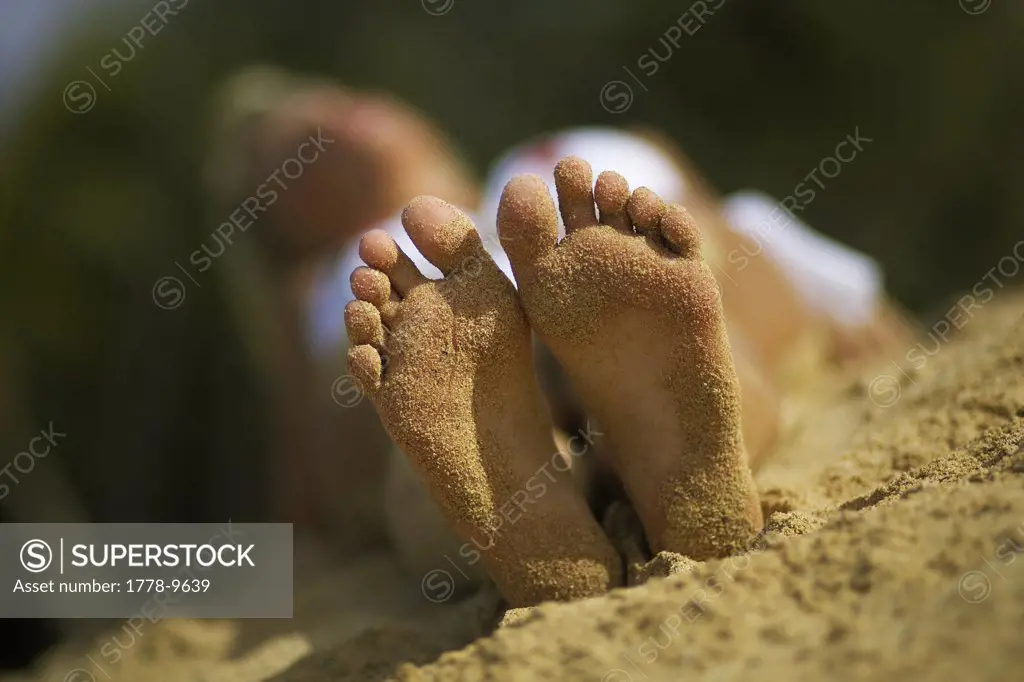 Young woman with sand on her feet sunbathing in bikini on beach in Lanai Hawaii