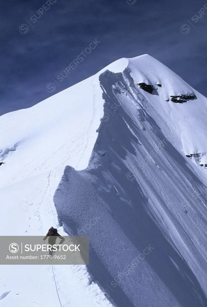 A mountain climber approaches the summit of Pequeno Alpamayo, Cordillera Real, Bolivia