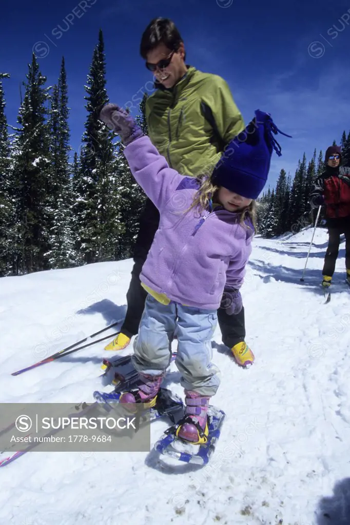 A father helps his daughter snowshoe, on a trail outside Breckenridge, CO