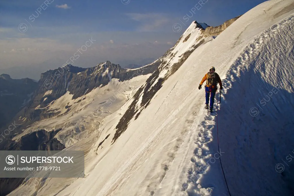 Mountain climber walking across snow ridge, Canada