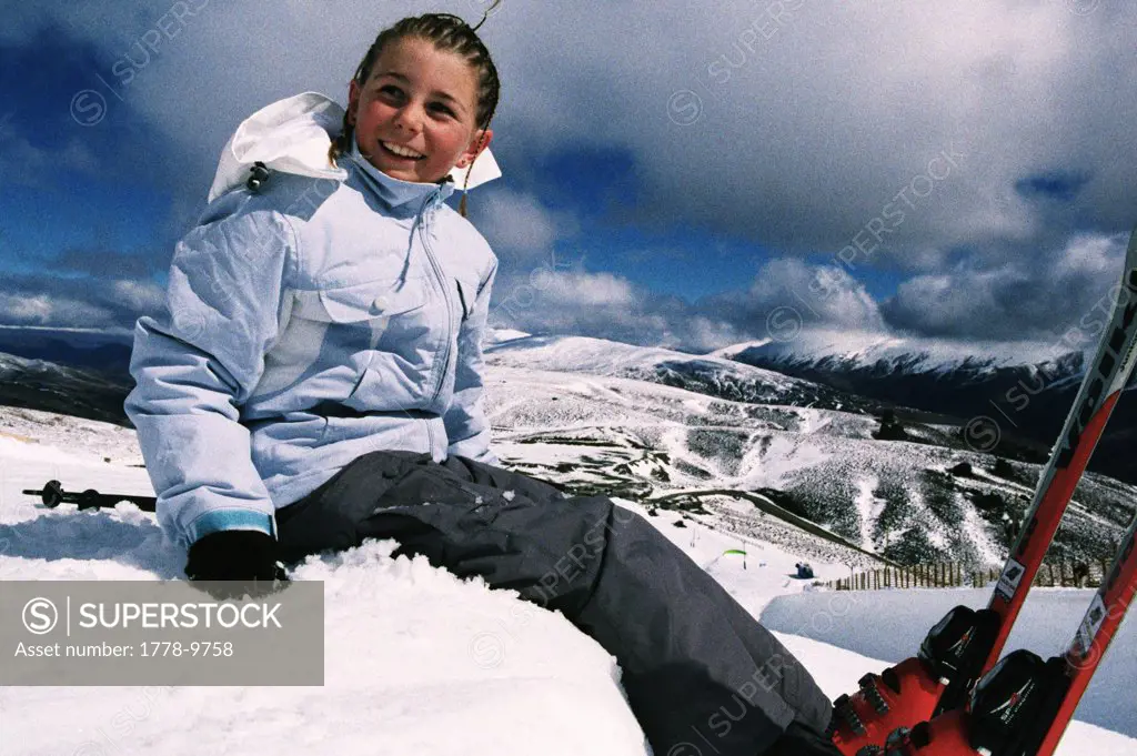 A girl waits on the side of a half pipe with skis