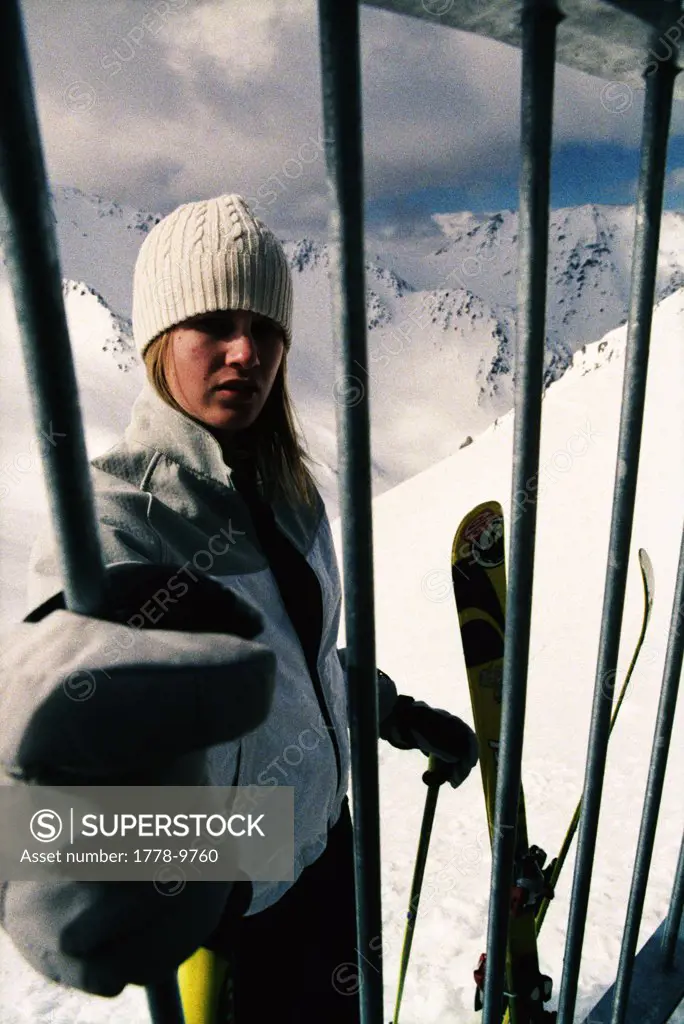 A woman stands behind a fence at a ski resort