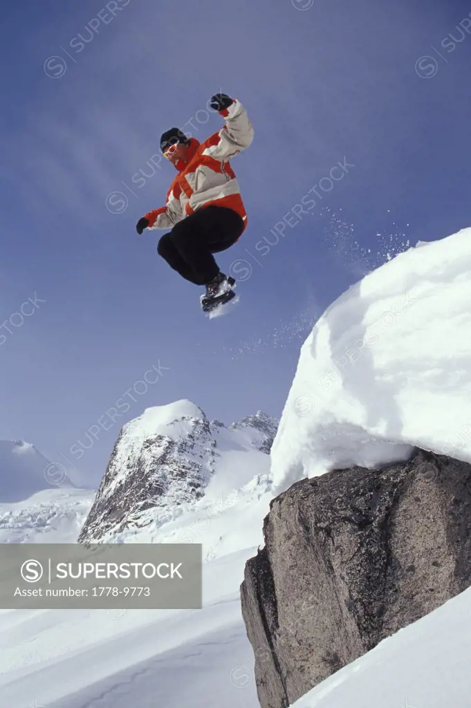 Young man leaps from cilff into fresh snow at Bugaboo Glacier Provincial Park, BC, Canada