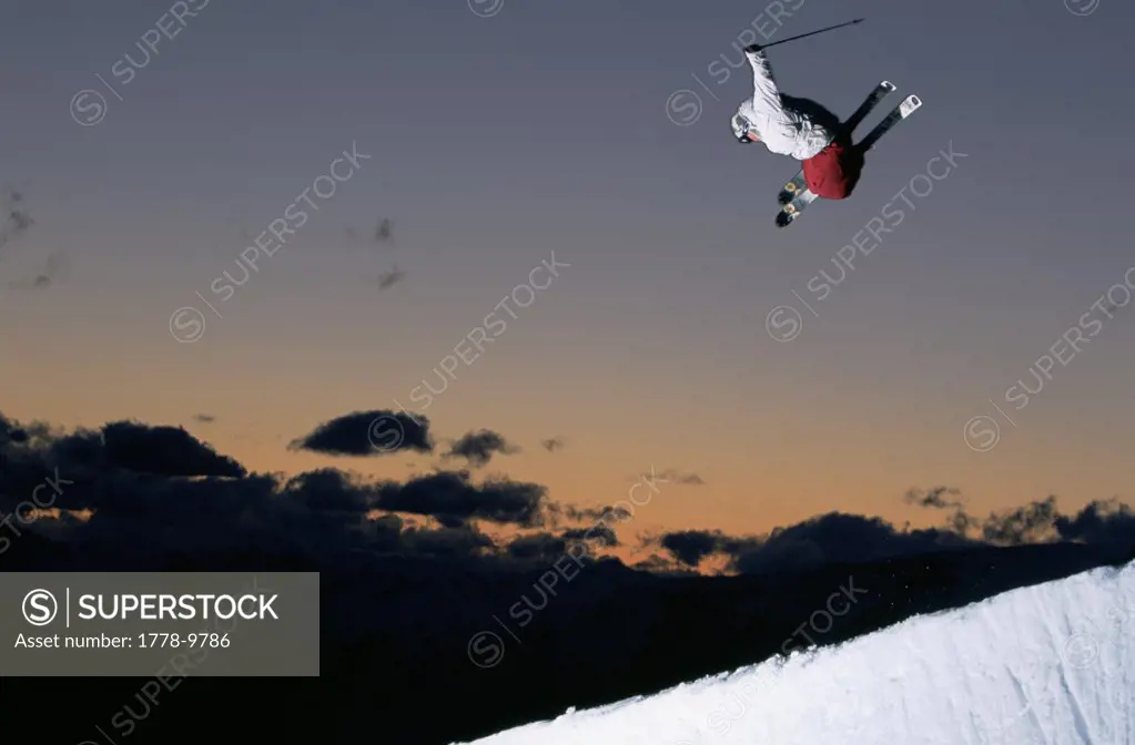 Skier jumps in half pipe at sunset