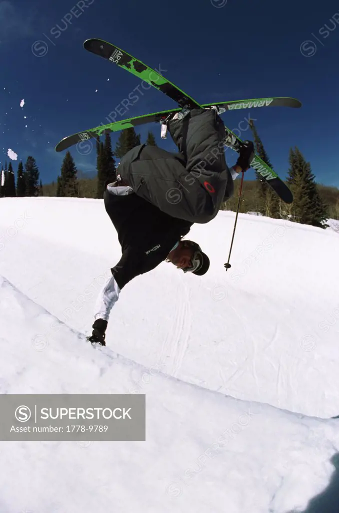 skier performs hand plant in half pipe