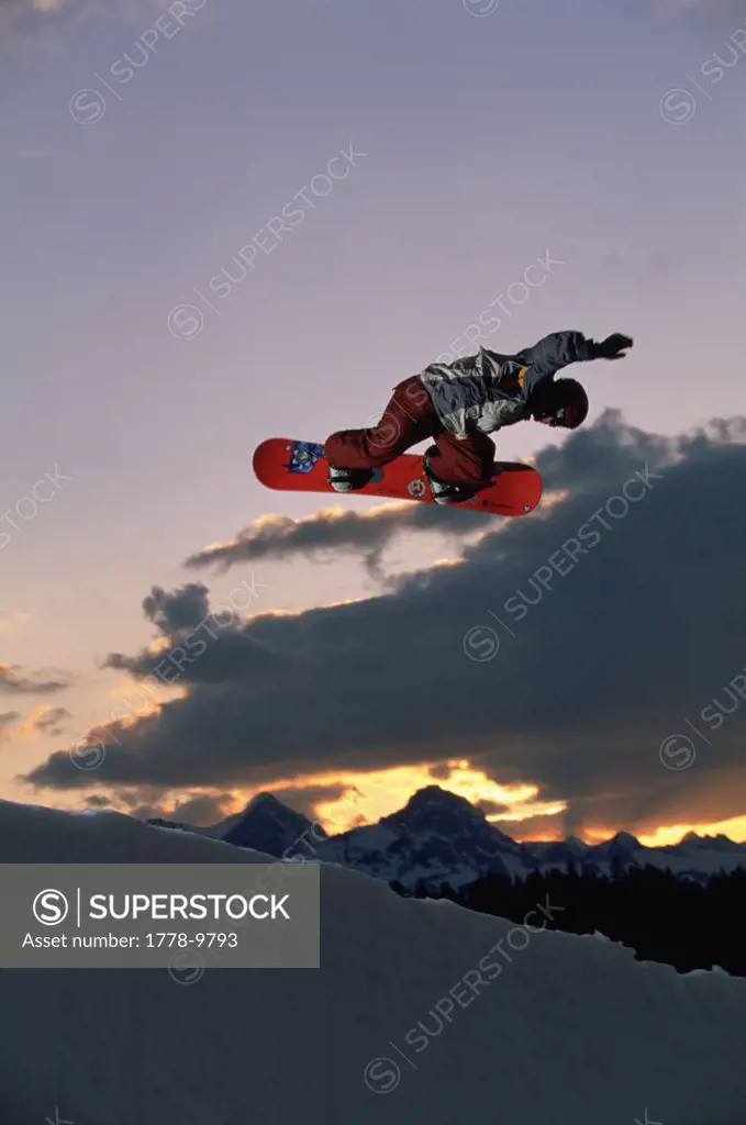 Snowboarder performs an air at sunset