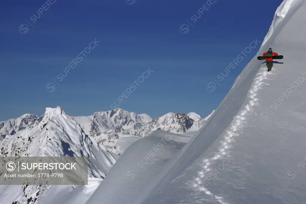 Snowboarder hikes a mountain in Alaska