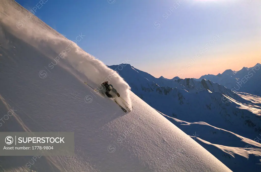 Skier rips a powder turn at twilight in alaska