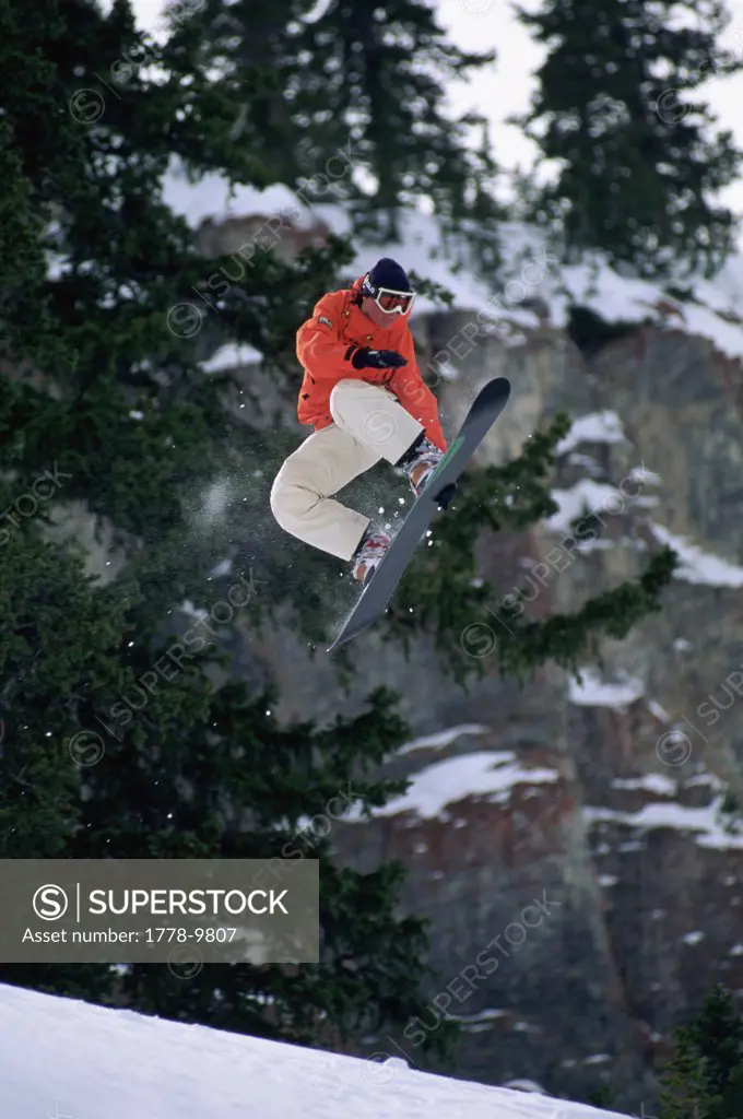 Female snowboarder catches some air in the backcountry