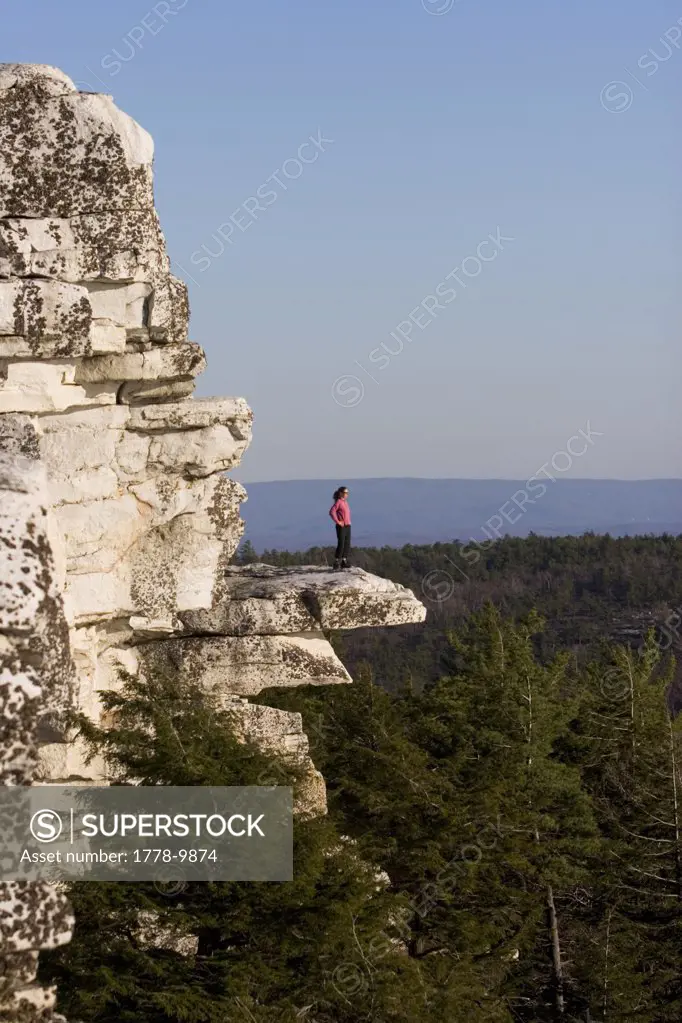 A woman takes a break from hiking to admire the view from a scenic overlook