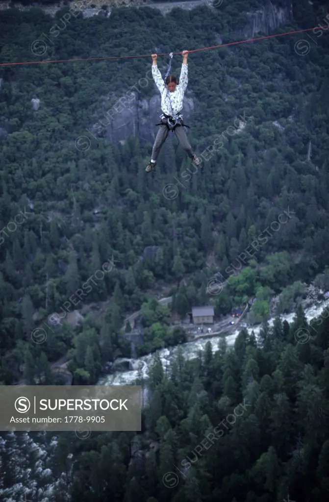 A man dangling from a rope one-thousand feet above the Merced River
