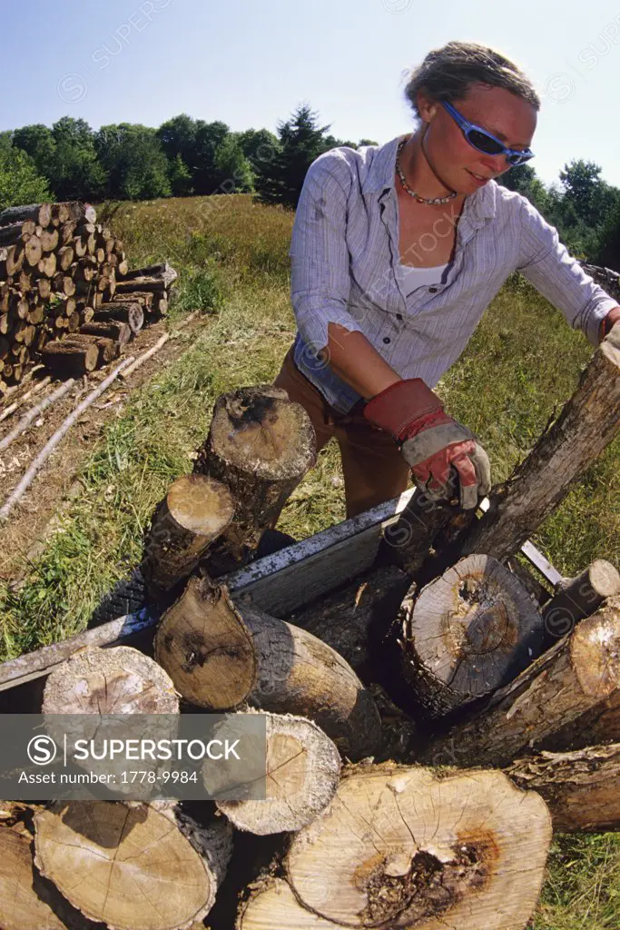 Woman stacking logs after chopping wood Manitoulin Island, Ontario