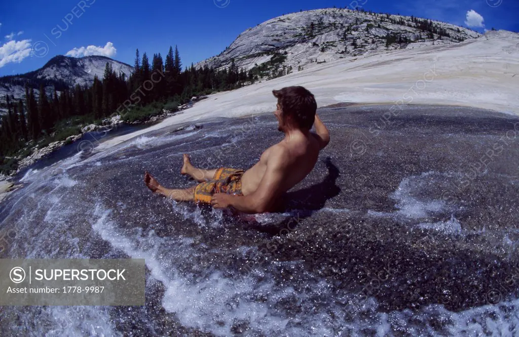 Man with hands up slides down an all natural granite waterslide in the Sierra Nevadas September 2004