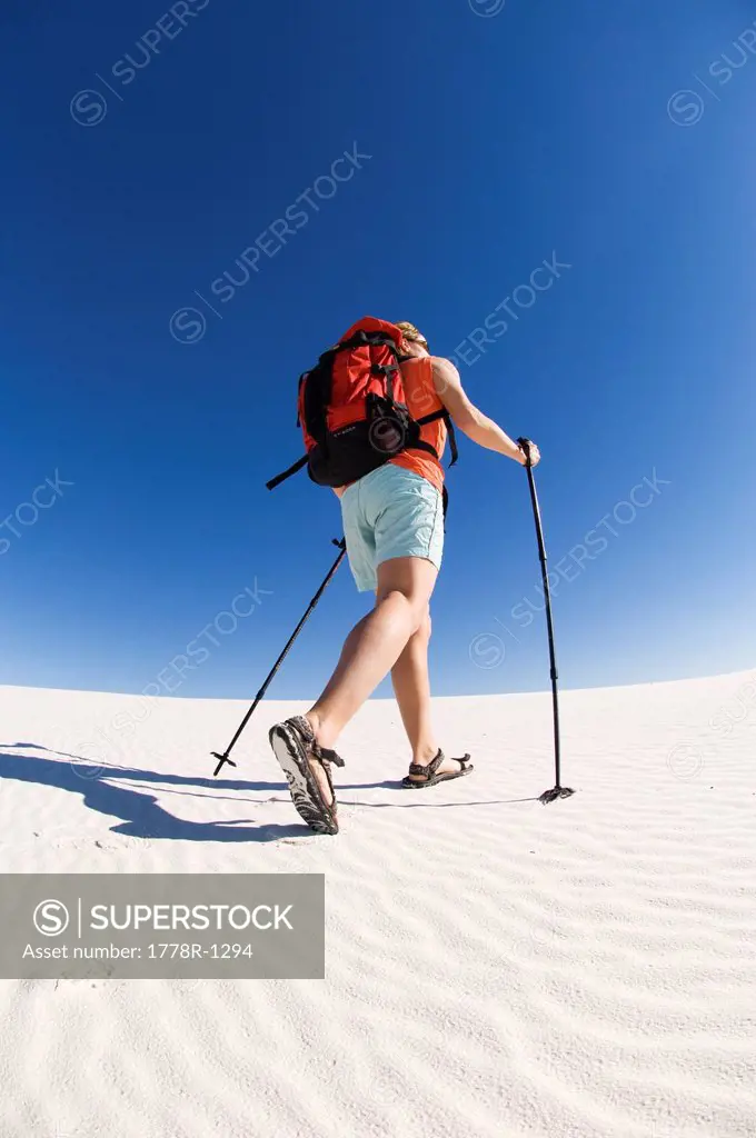 A woman hiking across sand dunes.