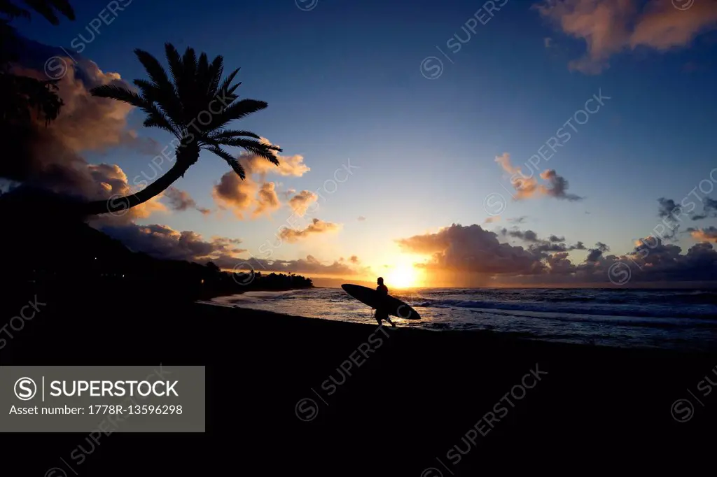 Surfer comes in at sunset