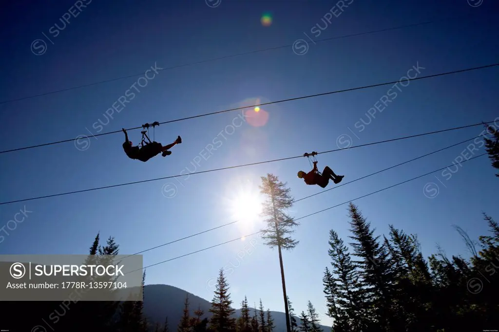 Two people ride a zip line in Whitefish, Montana.
