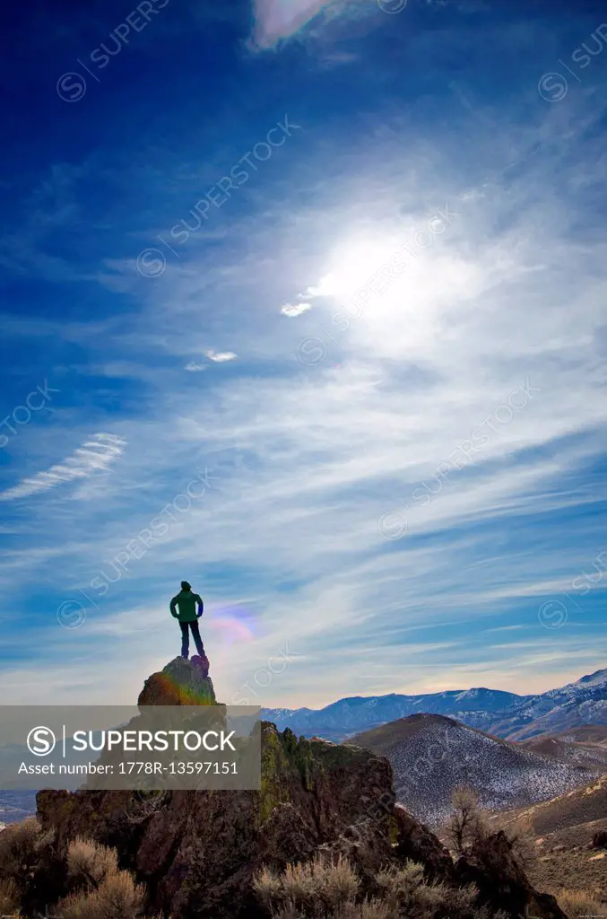 A woman stands on top of a large rock pile.