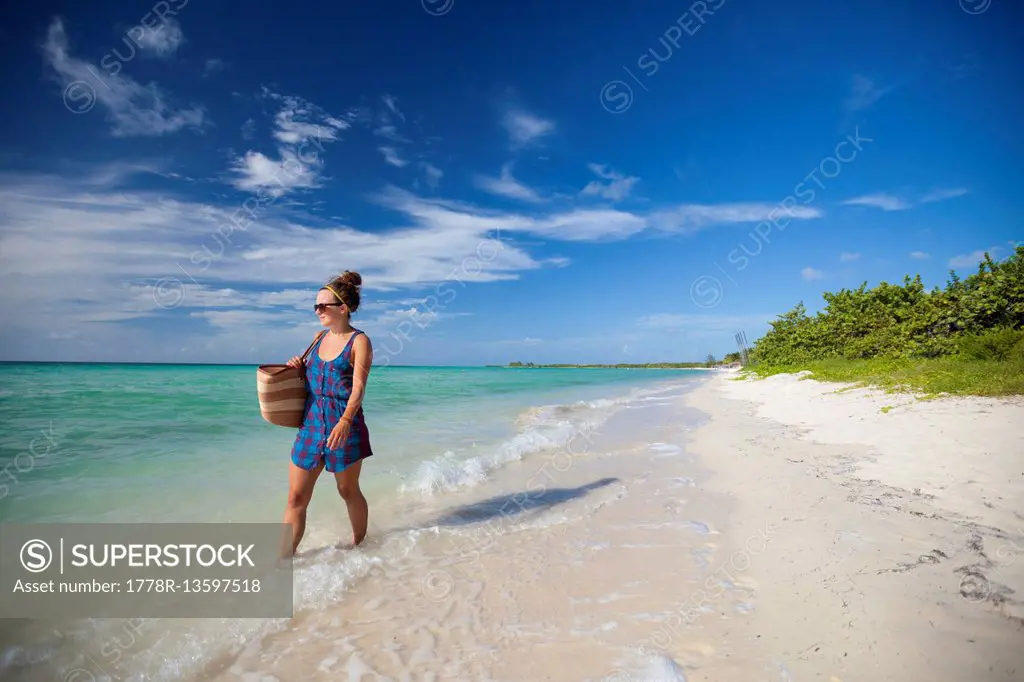 A young woman walks the shoreline of a beach in Cayo Coco, Cuba.
