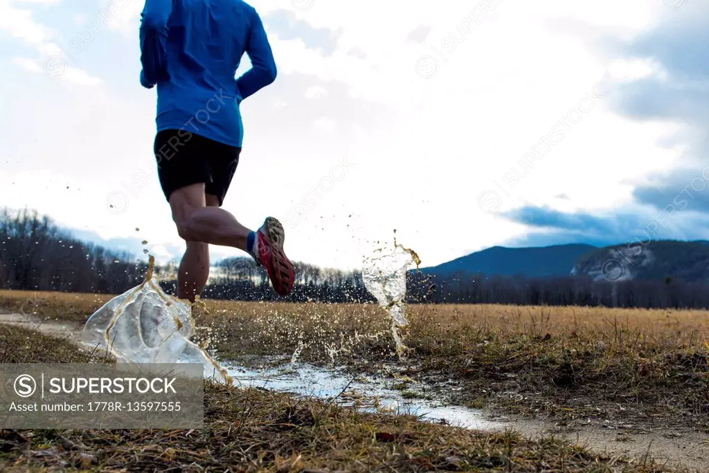 Trail runner splashing through a puddle.