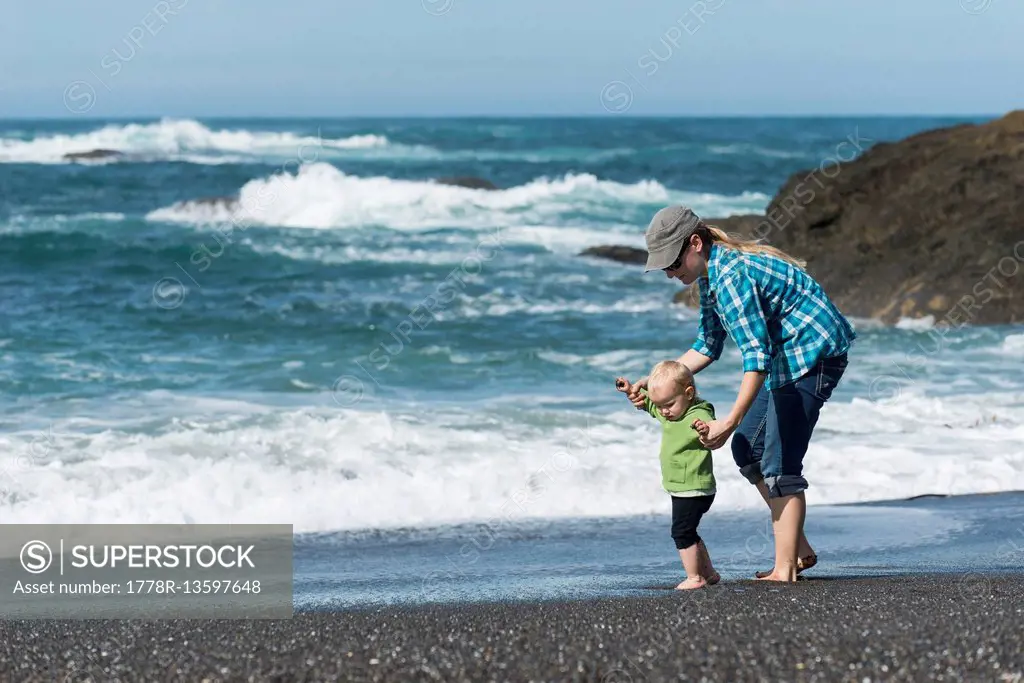 Mother playing with her young daughter on the beach along the California Coast