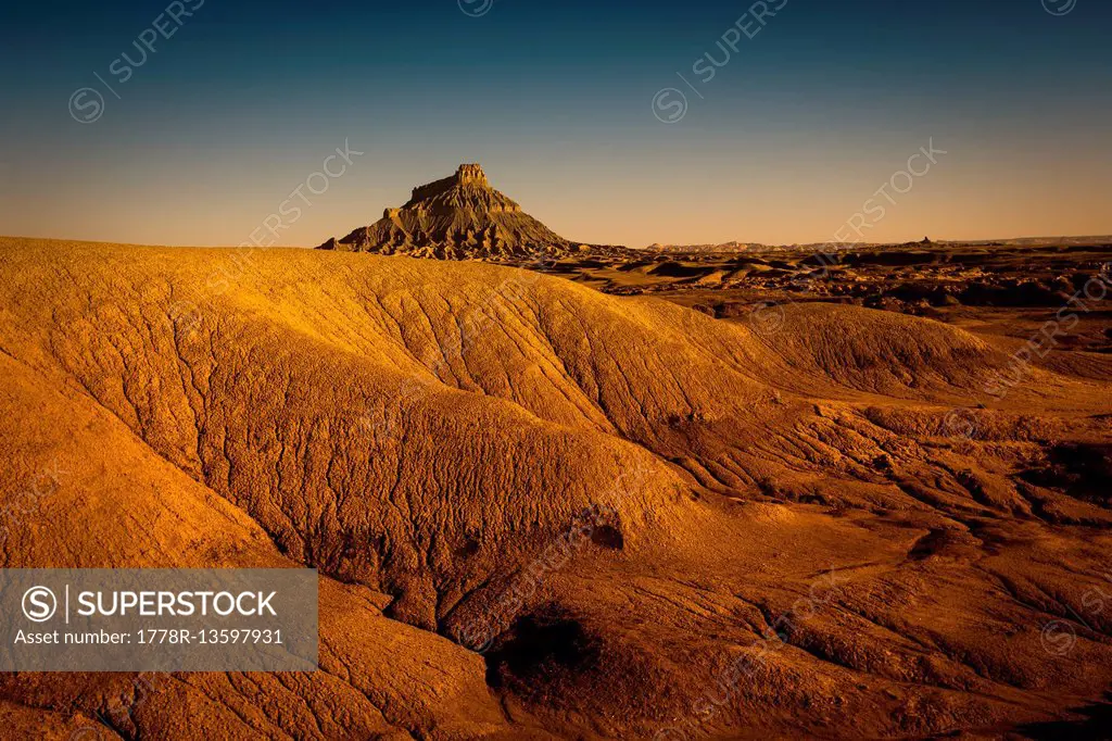 A stark desert landscape with a formation in the distance.