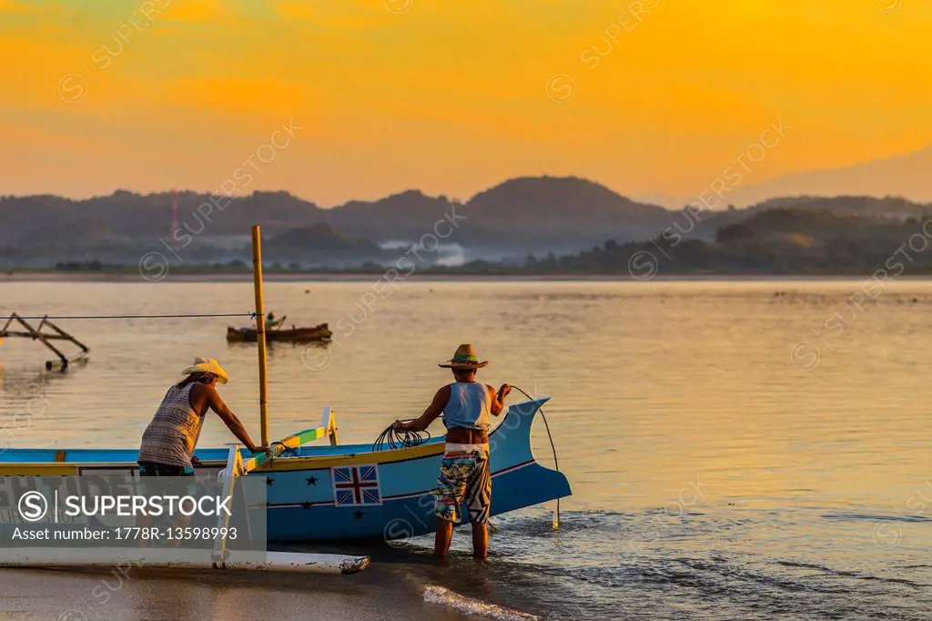 Indonesian men with a boat at sunrise time.
