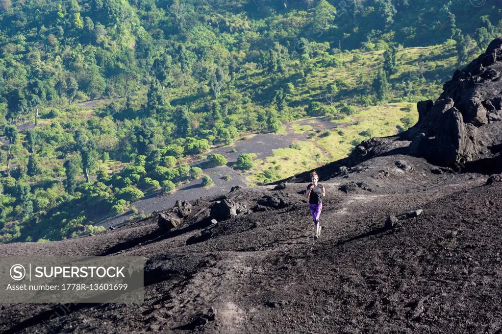 A Young Athletic Female Trail Runner Running On The Black Sands Of The Pacaya Volcano, Guatemala