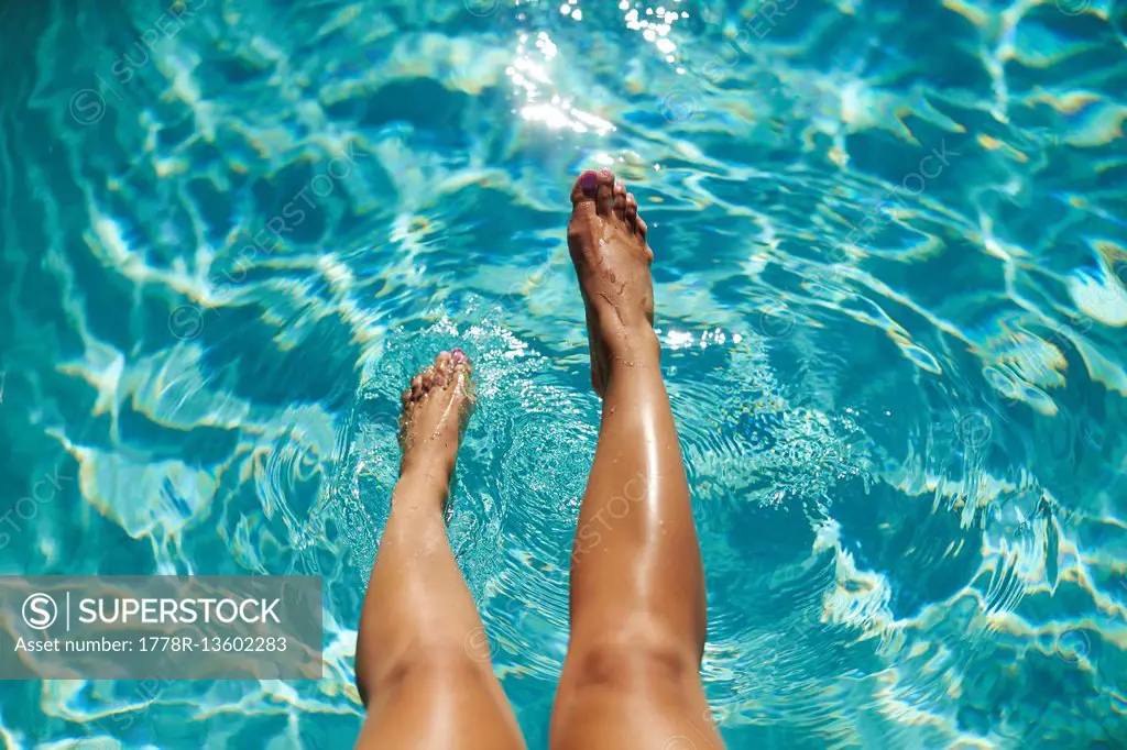 Close-up Of Young Woman Leg In Turquoise Water Of Pool