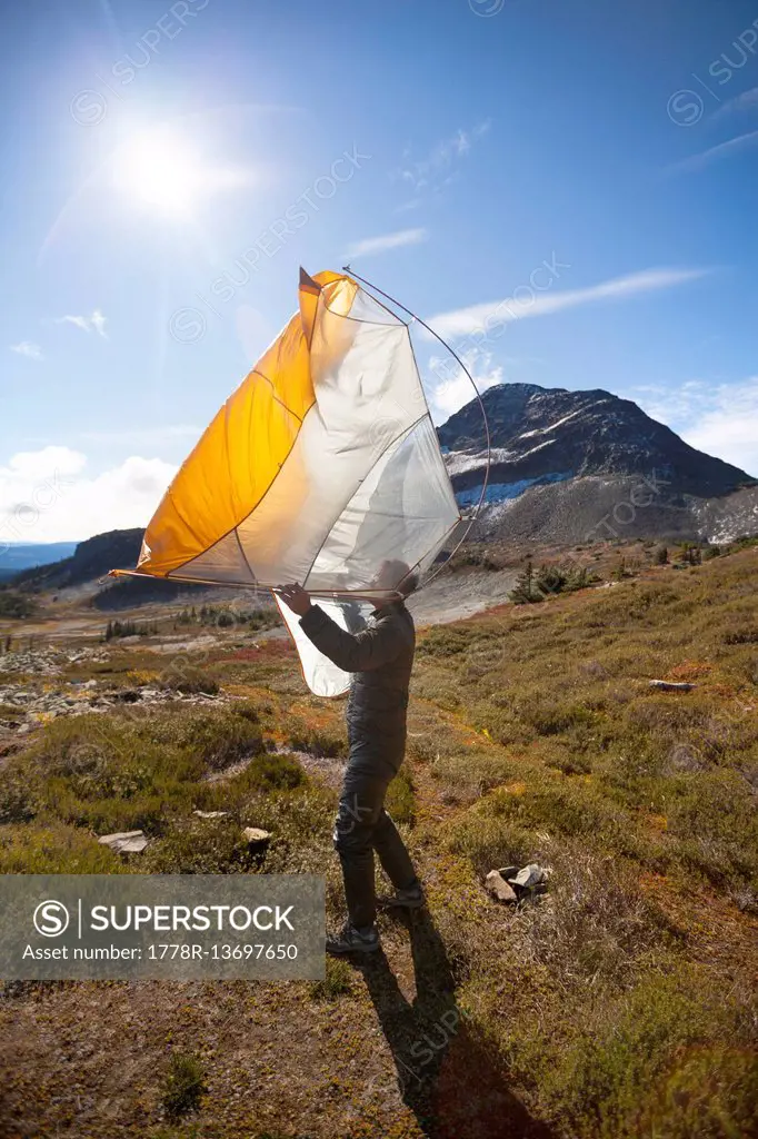 A Hiker Shakes Out His Tent Below Jim Kelly Peak In Illal Meadows