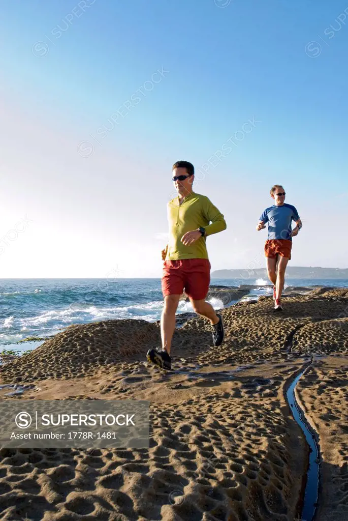 Runners on rocky Pacific coast.
