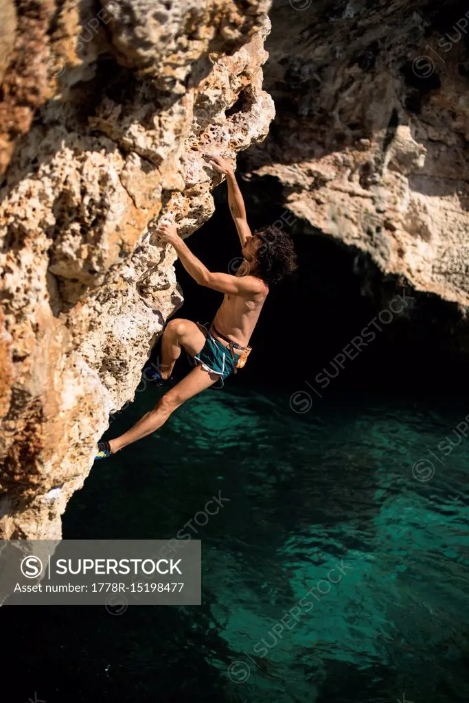 Man doing psicobloc in Mallorca, Spain. Psicobloc is a rock climbing discipline where the climber climbs without rope and other safety gear on selloff...