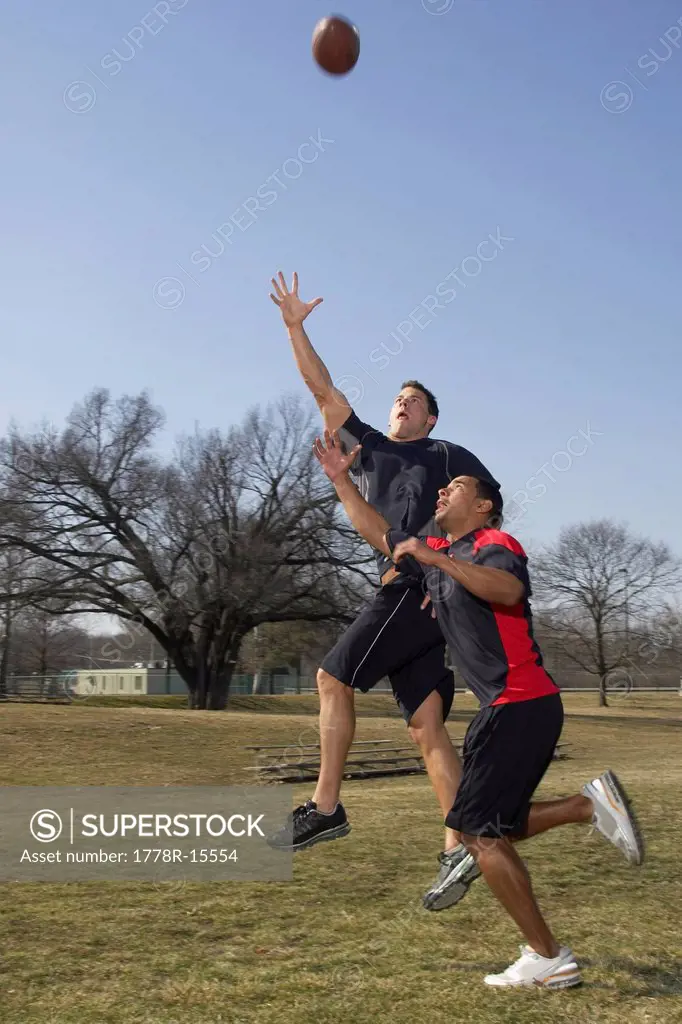 Two men in their twenties playing touch football competeing for pass.