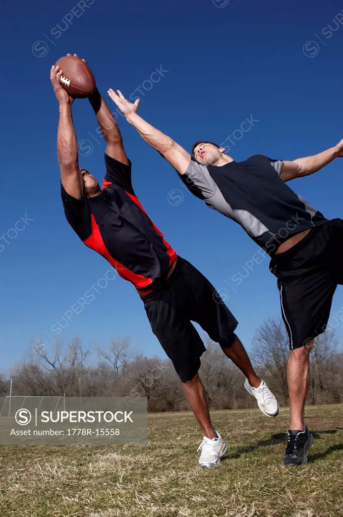 Two men compete for a pass in a touch football game.