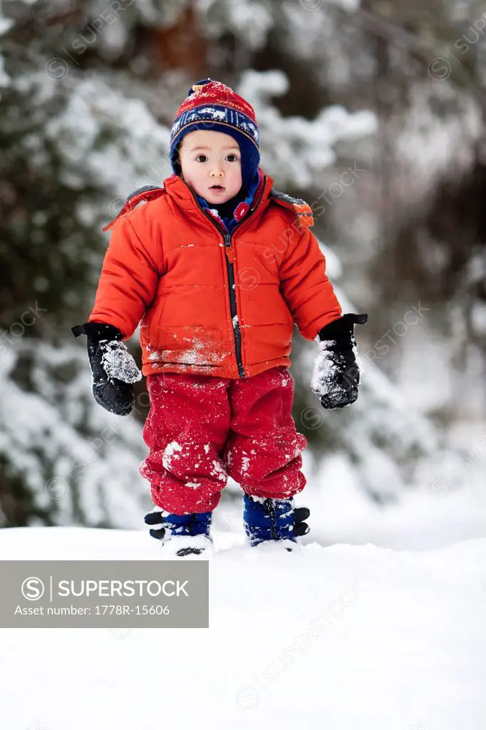 An almost two year old boy, walks through snow on a winter day in Fort Collins, Colorado.