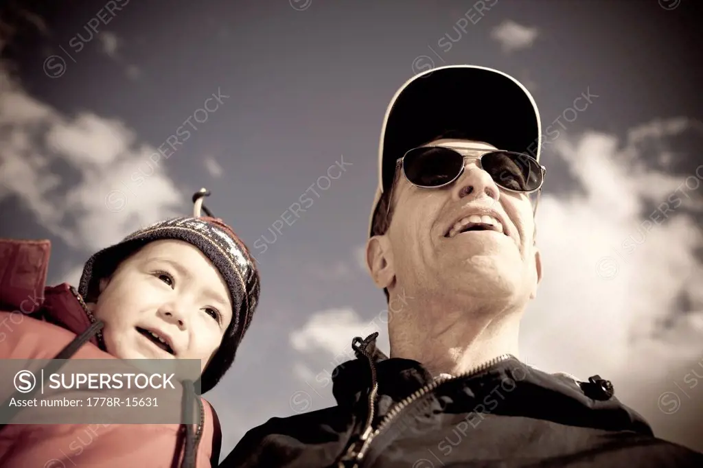 A two year old boy is held by his grandfather, an active senior, on a blue sky day in the mountains of Colorado.