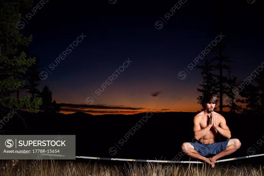 A professional slackliner plays around on the slackline in a field at sunset in the Blue Mountain of Missoula, Montana.