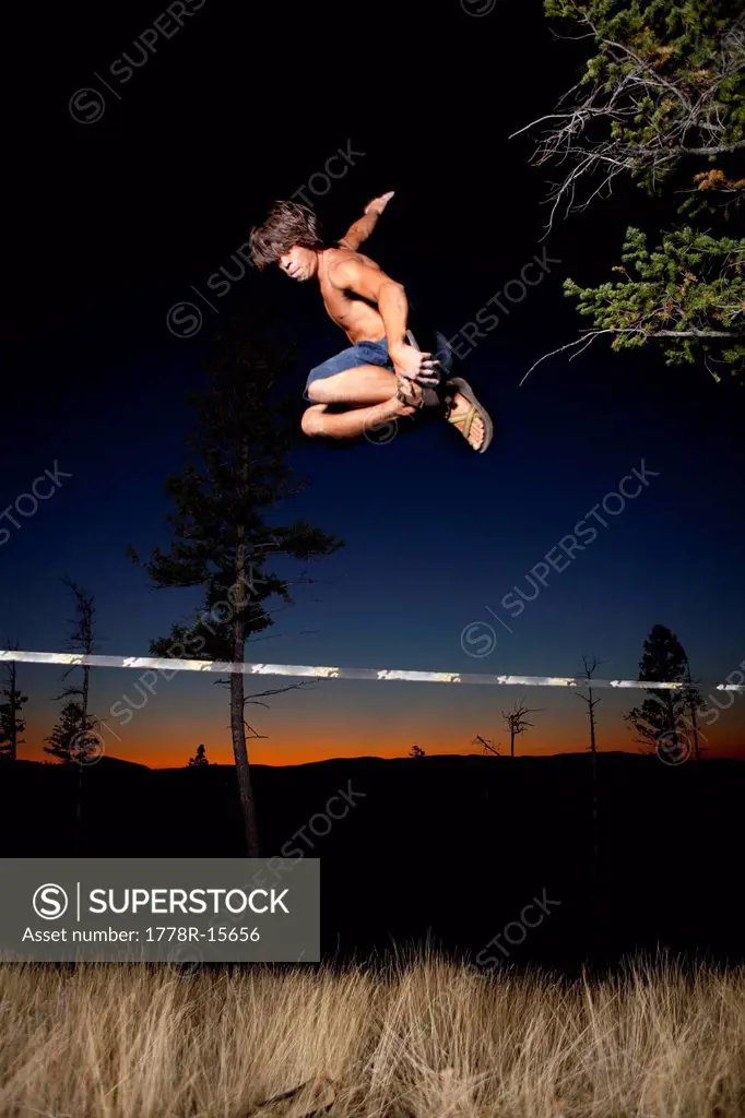 A professional slackliner plays around on the slackline in a field at sunset in the Blue Mountain of Missoula, Montana.