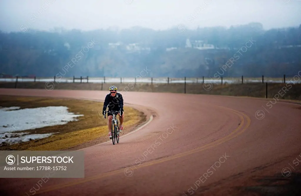 Man bicycles on a cold and foggy winter day.