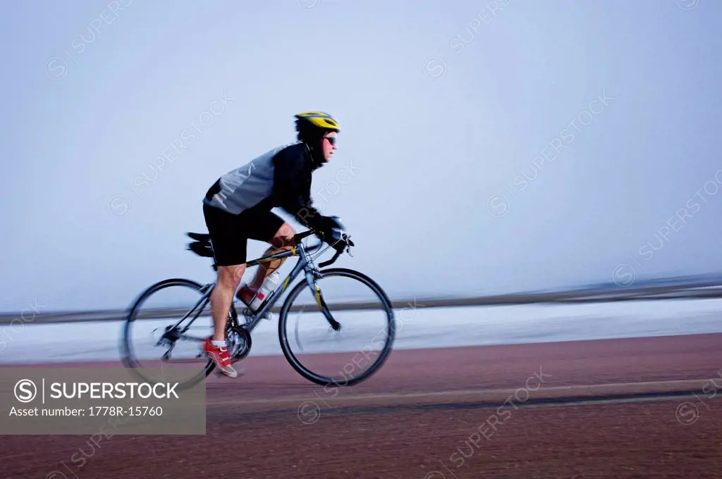 Man bicycles on a cold and foggy winter day.