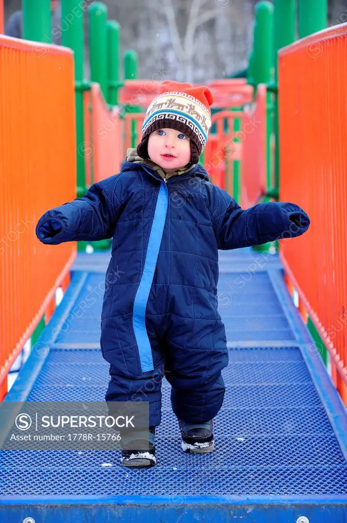 Toddler plays on the playground in the winter.