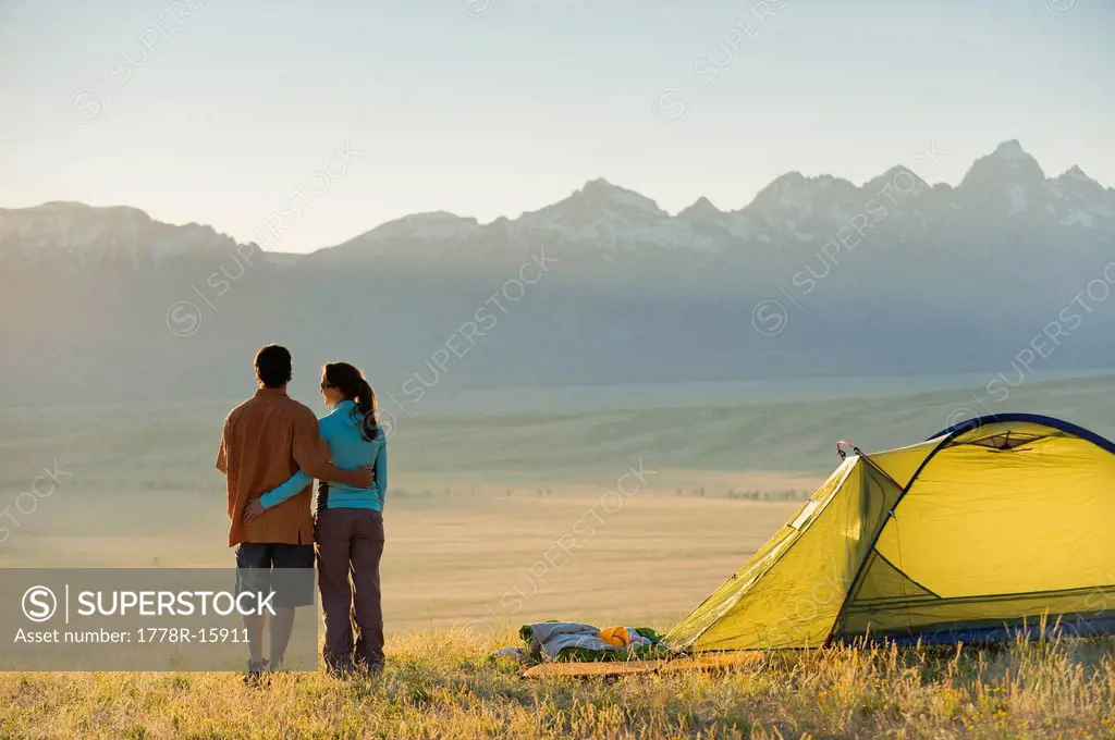 A young couple enjoy the last rays of the day while camping.