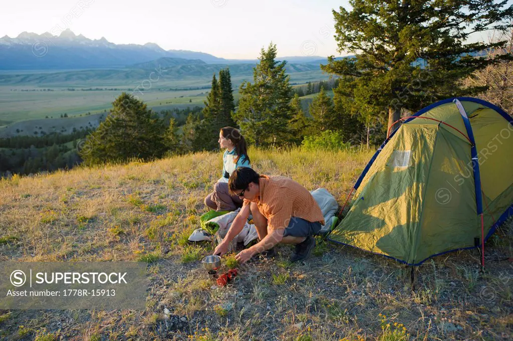 A young couple camp on a summer evening.
