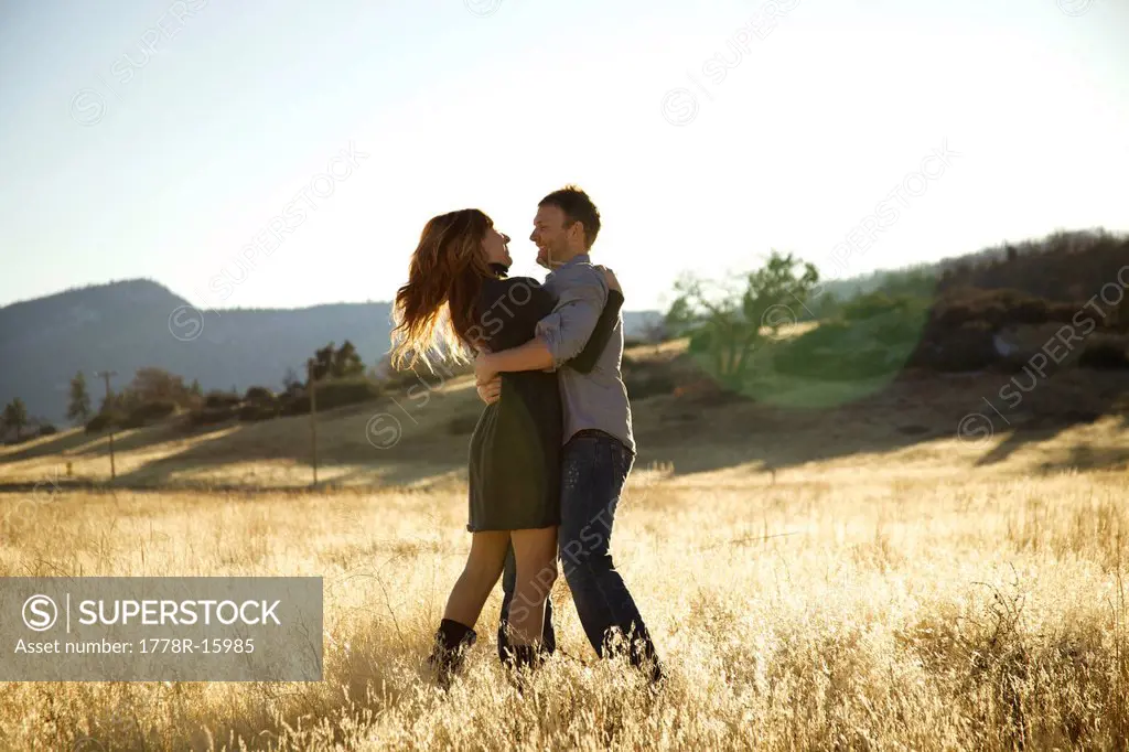 Happy couple hugging in an open field.