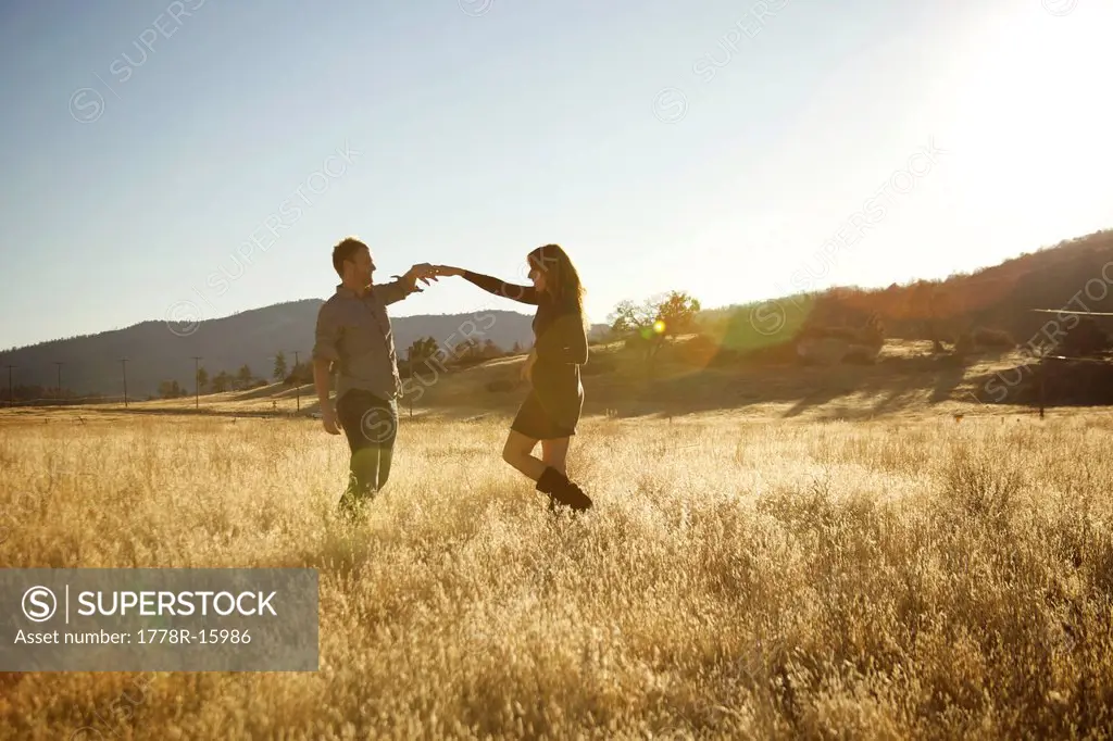Happy couple dancing in an open field.