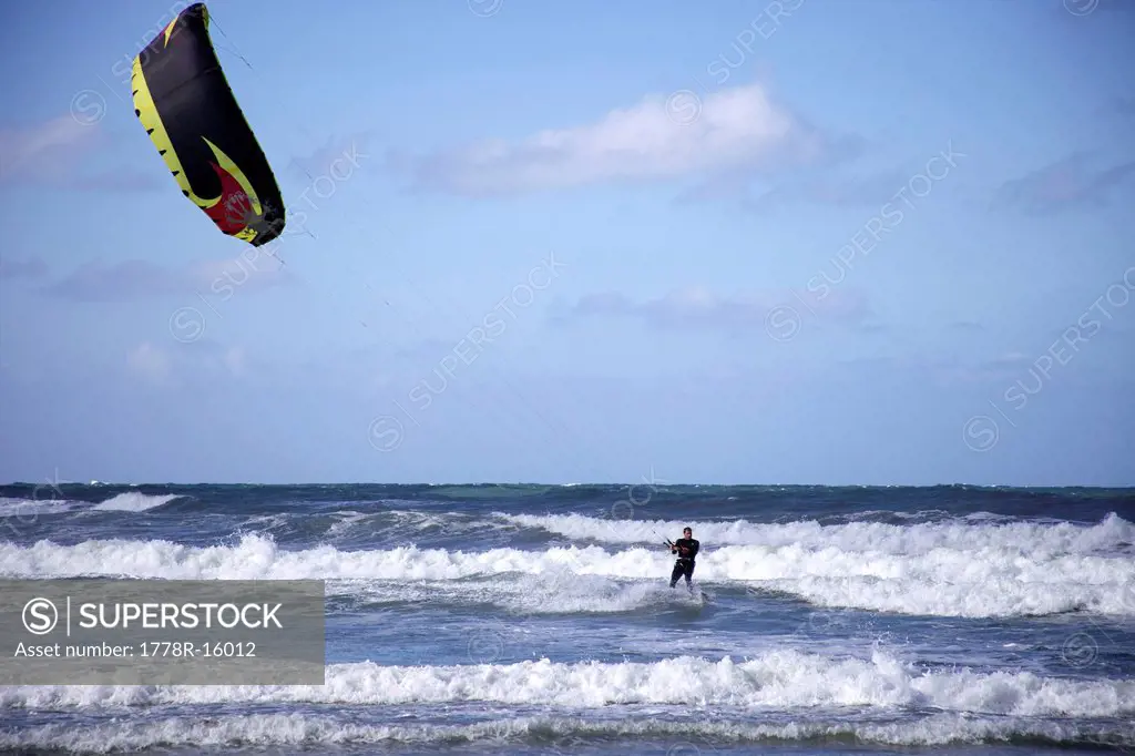 Male kitesurfer rides a small wave.